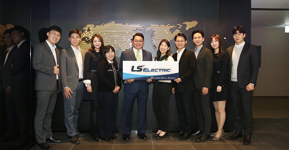 Koo Ja-kyun, presidente de LS Electric (en el centro), sostiene un cartel con el nuevo logo de la compañía junto a varios empleados, en la sede de la corporación.